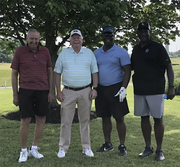 Group of golfing men posing for photo outdoors